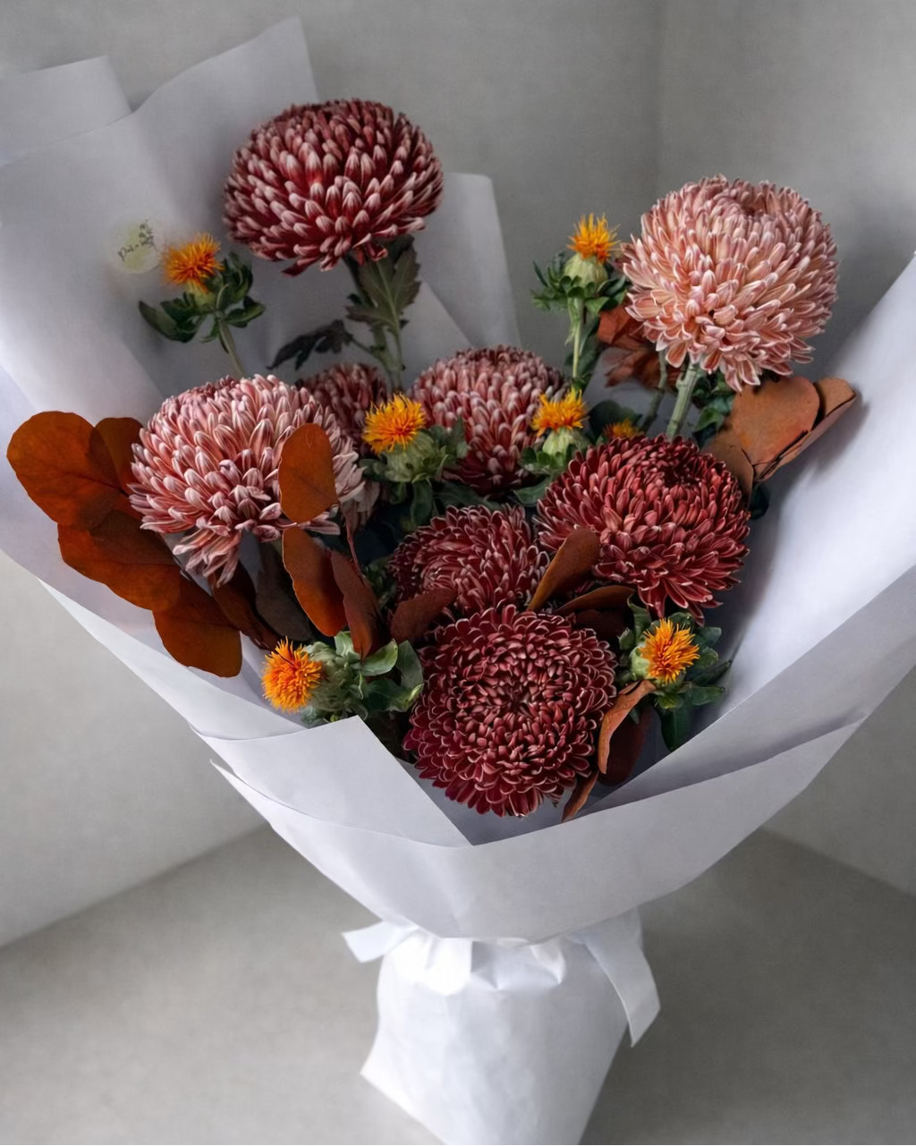 Bouquet of flowers wrapped in white paper on a light gray background