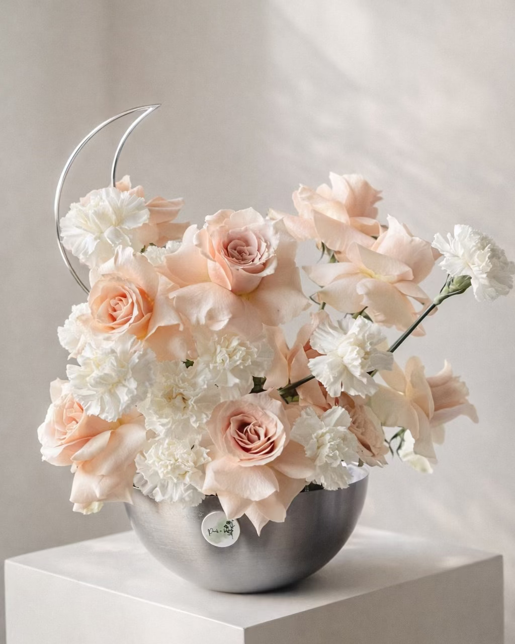 Floral arrangement with pink and white flowers in a silver vase on a white surface. Main image