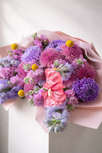 Bouquet of colorful flowers with a pink bow on a white background