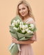 Woman holding a bouquet of white tulips against a beige background