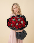 Woman holding a bouquet of red roses against a beige background