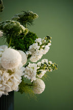 Close-up of a bouquet of white and green flowers against a green background